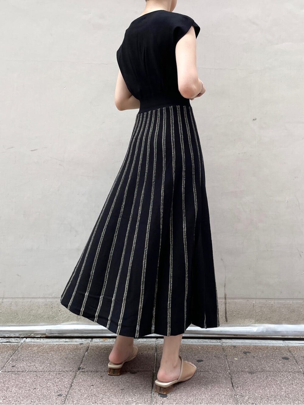 レッド系のサンダル、ブラック系のワンピースを着用したレディースの夏コーディネートの2枚目の写真