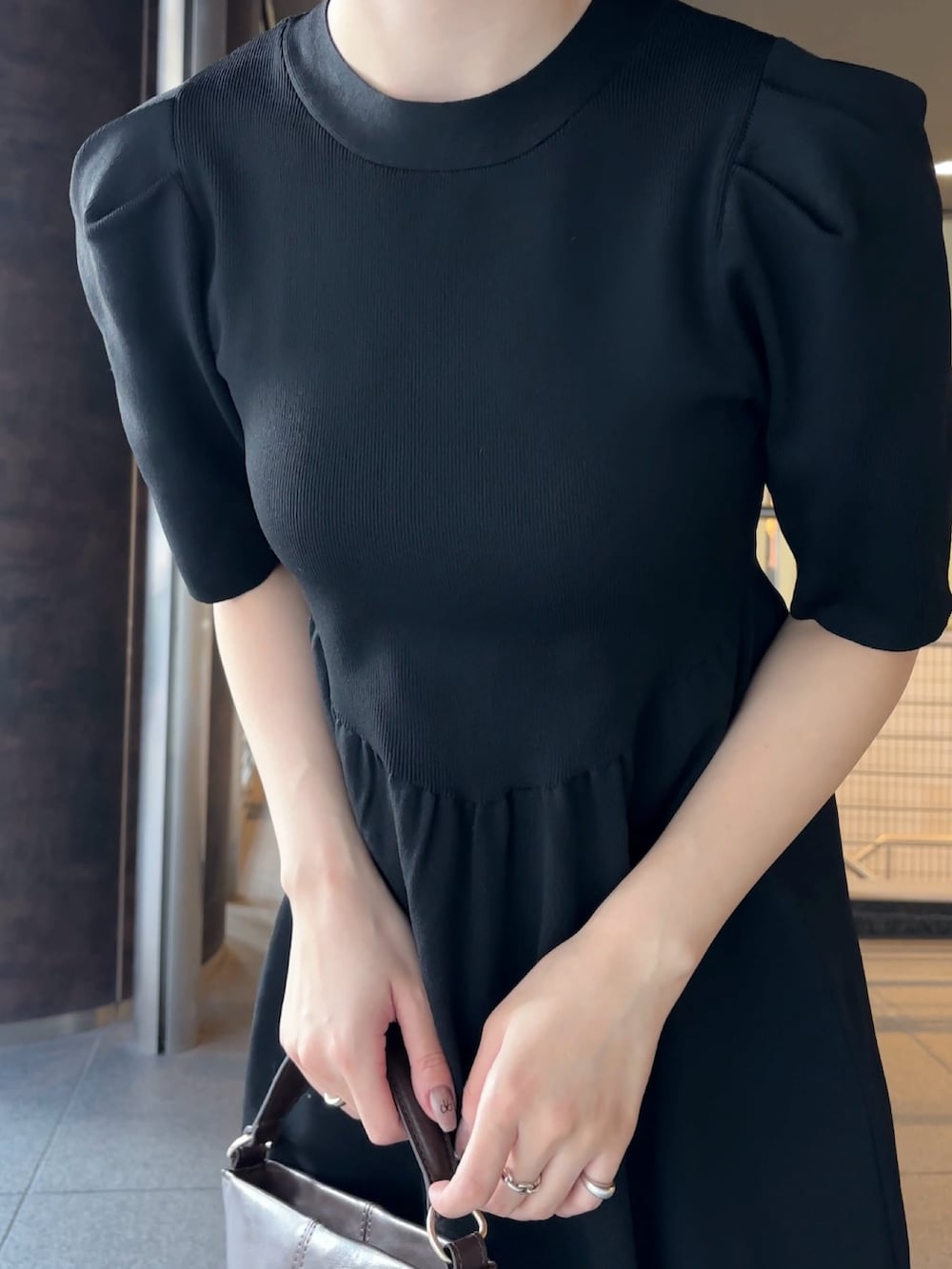 ブラウン系のハンドバッグ、シルバー系のパンプス、ブラック系のワンピースを着用したレディースの冬コーディネートの5枚目の写真