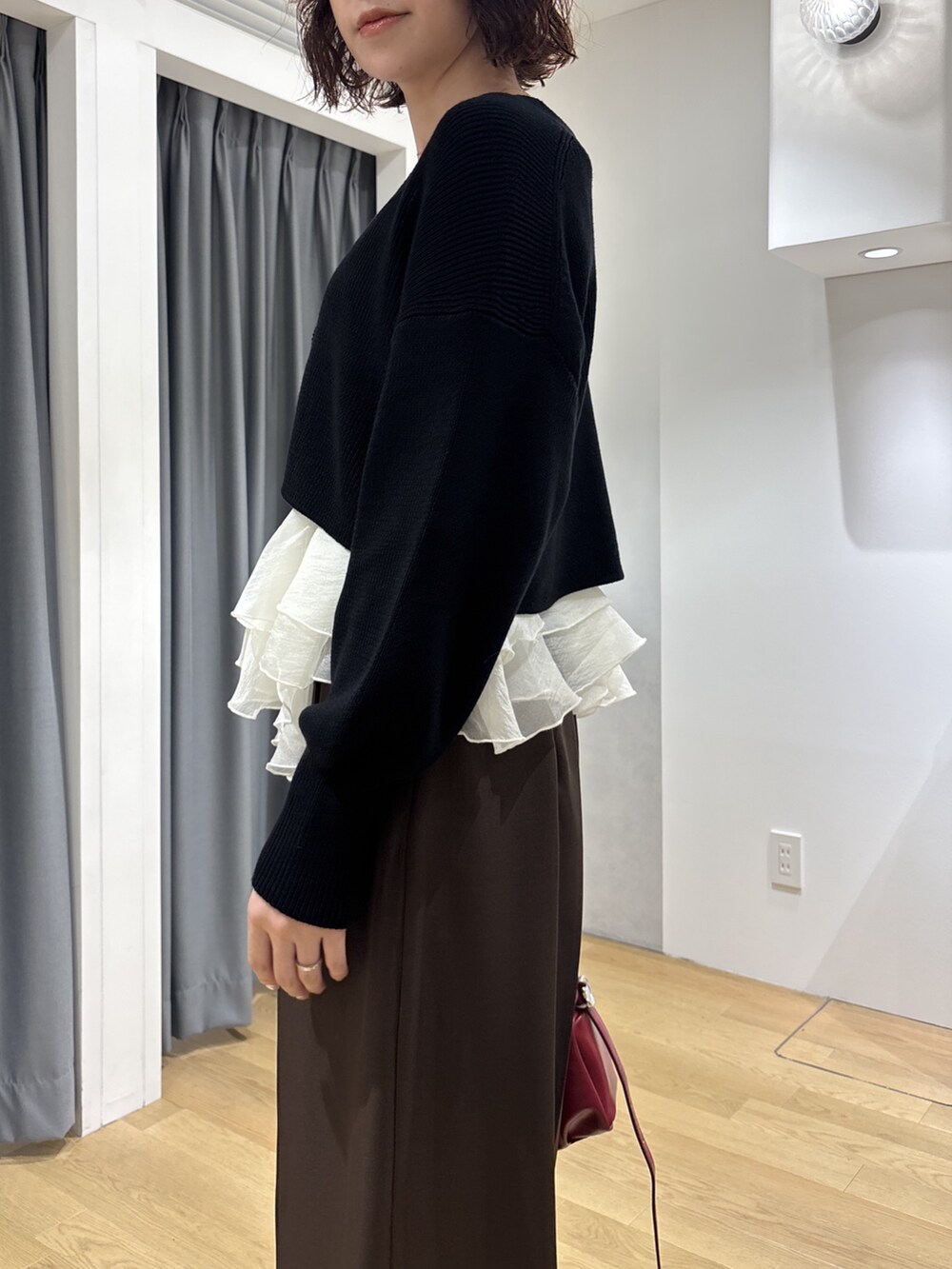 ブラウン系のその他パンツ、ブラック系のカーディガン/ボレロ、レッド系のハンドバッグを着用したレディースの秋コーディネートの6枚目の写真