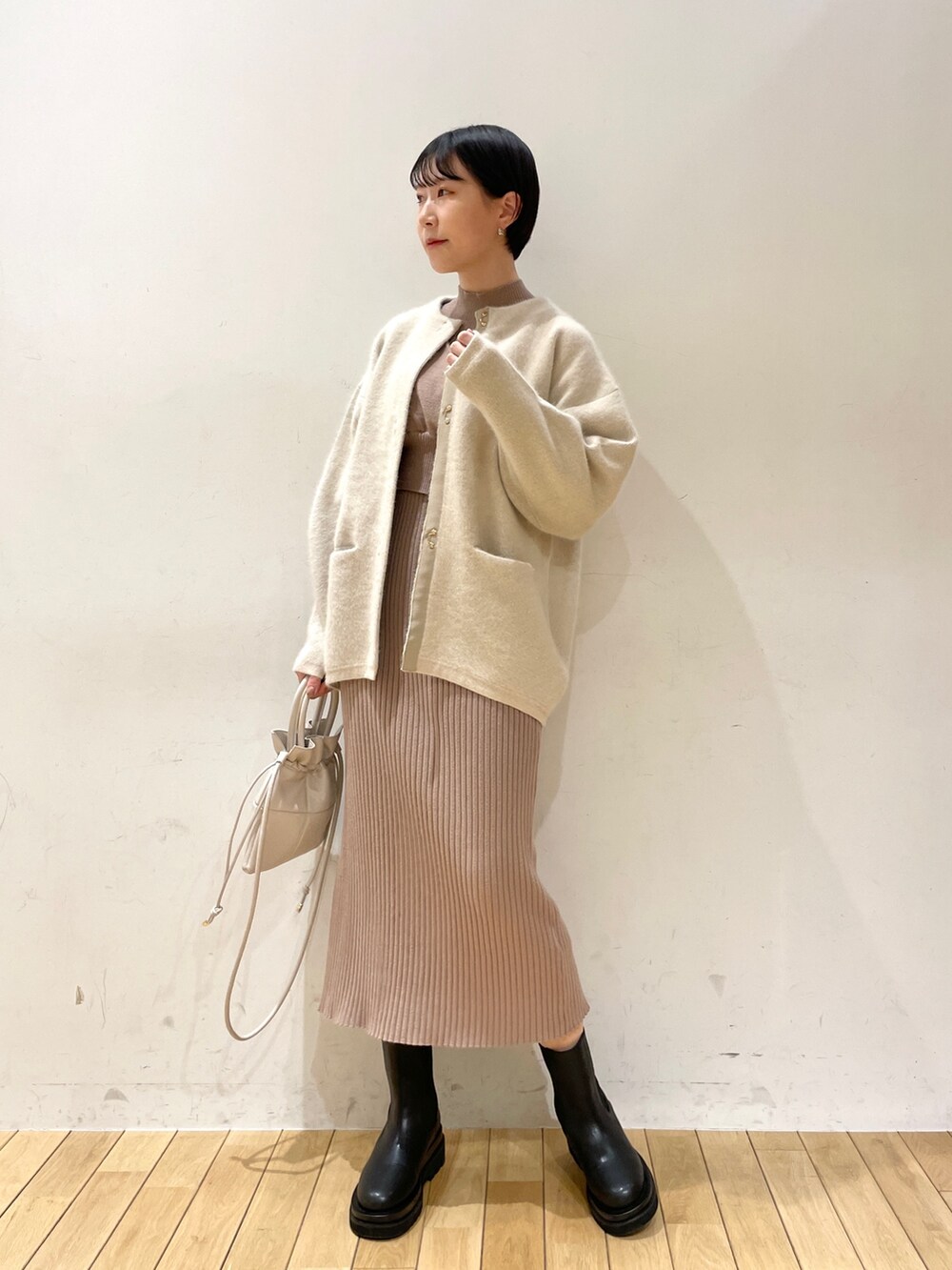 ベージュ系のワンピース、ホワイト系のハンドバッグ、ブラック系のブーツを着用したレディースの冬コーディネートの9枚目の写真