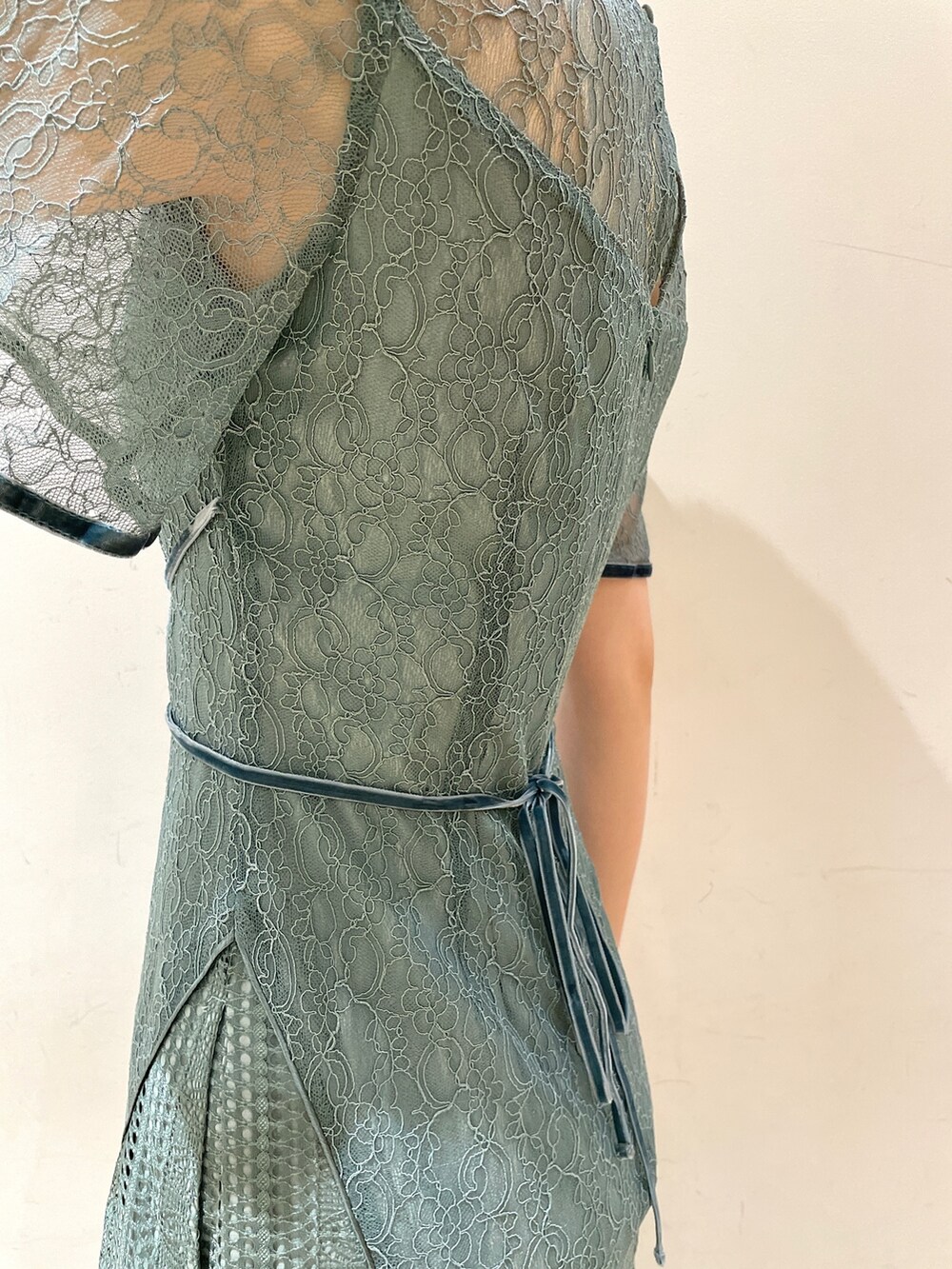 グリーン系のドレス、ベージュ系のクラッチバッグ、ゴールド系のパンプスを着用したレディースの冬コーディネートの9枚目の写真