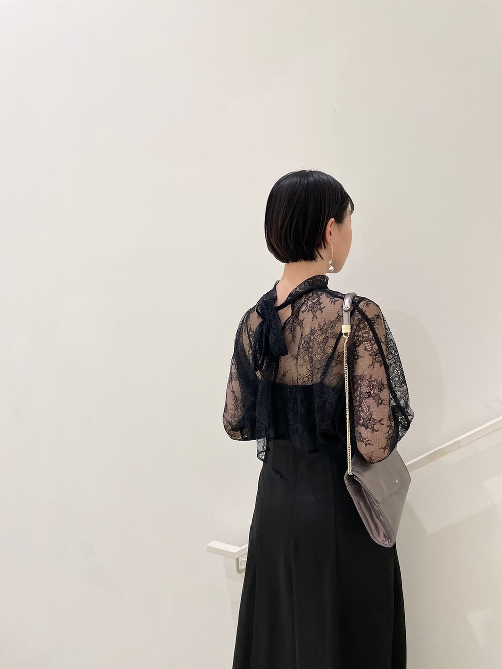 ブラック系のドレス、シルバー系のパンプス、シルバー系のハンドバッグを着用したレディースの春コーディネートの6枚目の写真