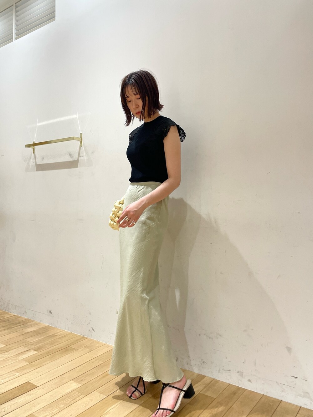 ベージュ系のハンドバッグ、ブラック系のサンダル、グリーン系のスカートを着用したレディースの夏コーディネートの2枚目の写真