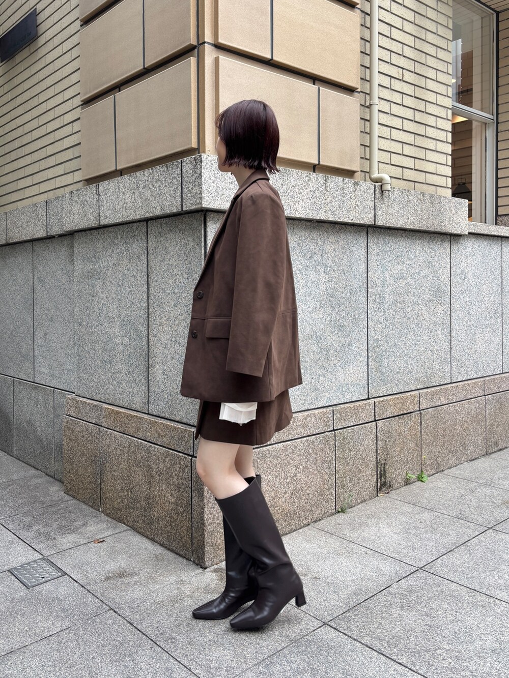 ブラウン系のブーツ、ブラウン系のハンドバッグ、ブラウン系のスカートを着用したレディースの秋コーディネートの5枚目の写真