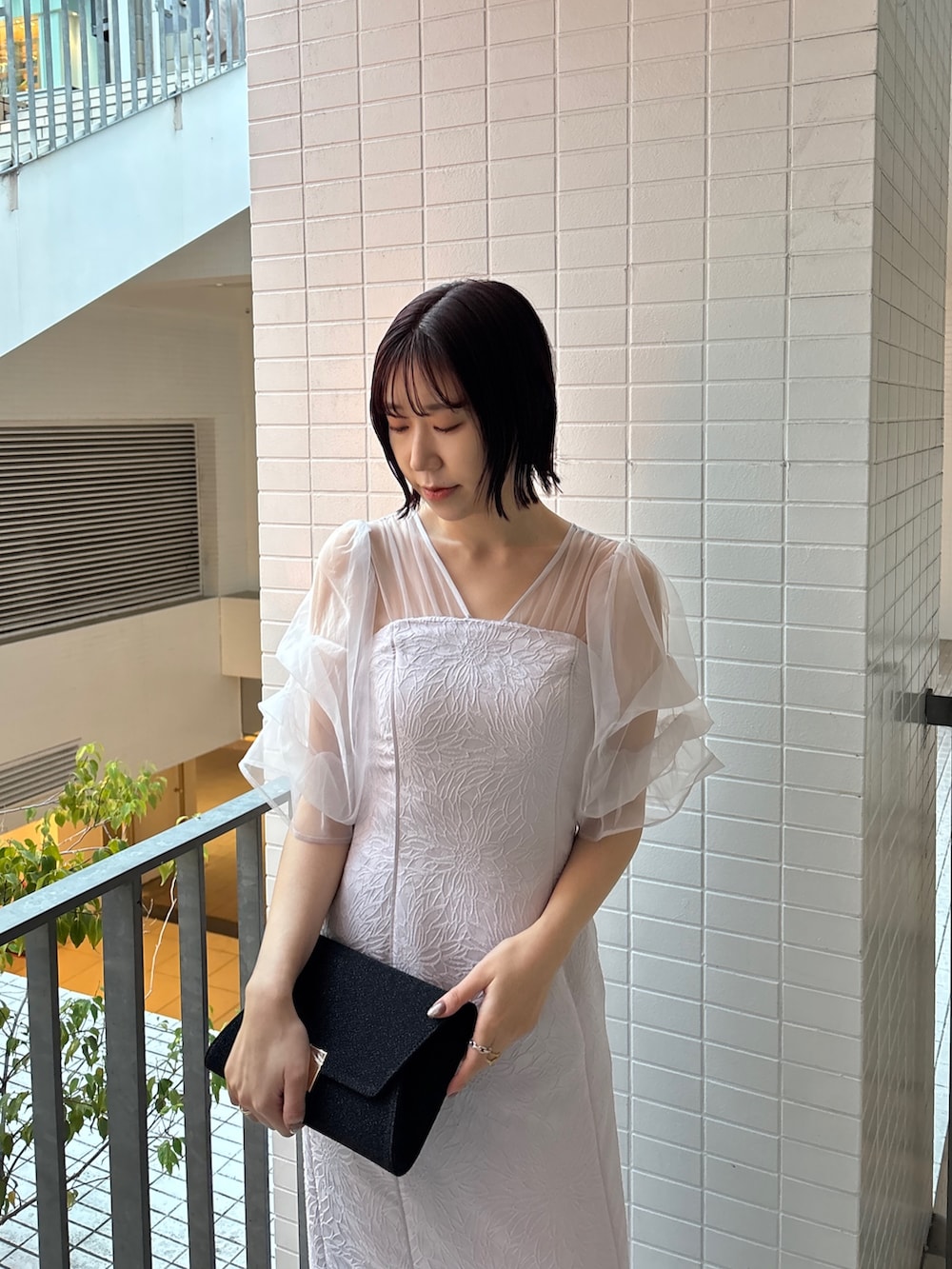 パープル系のドレス、ブラック系のハンドバッグ、ブラック系のパンプスを着用したレディースの冬コーディネートの5枚目の写真