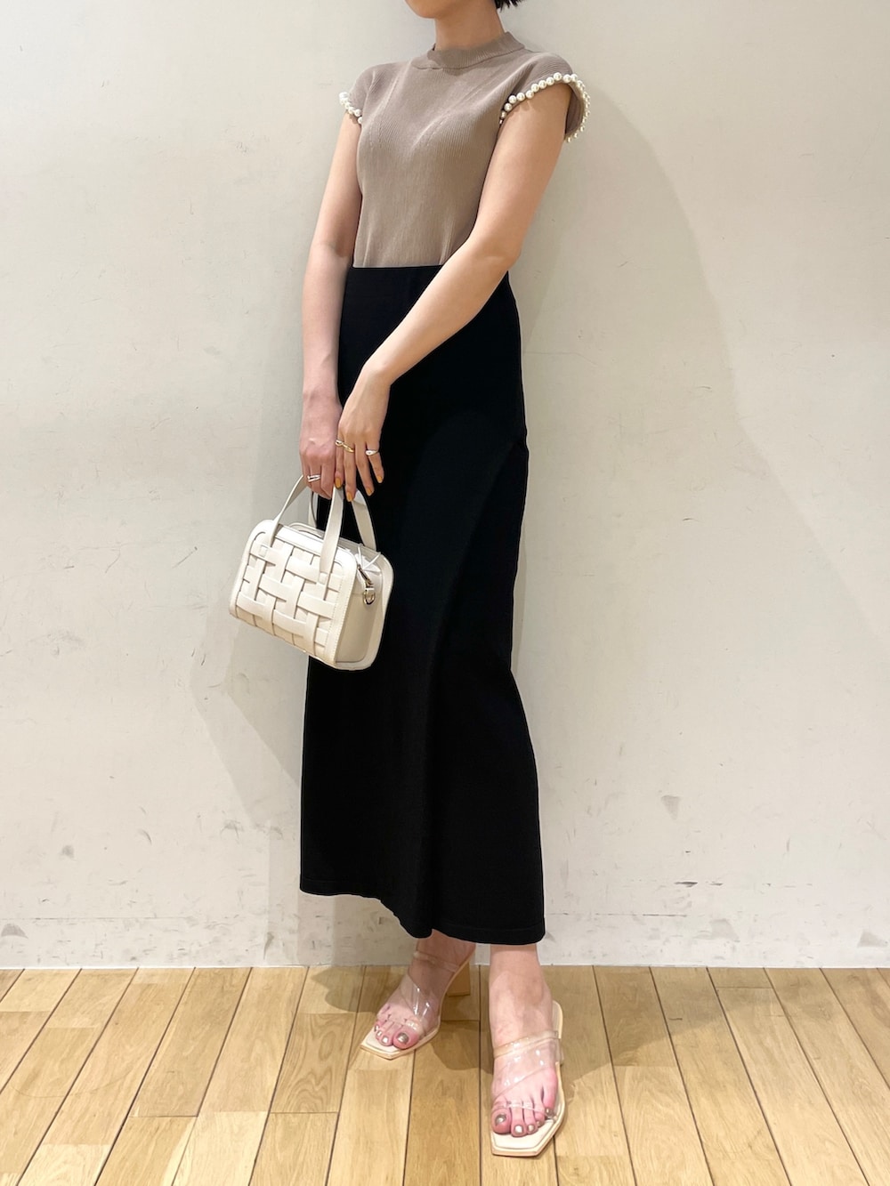ブラック系のスカート、ベージュ系のニット/セーター、ホワイト系のショルダーバッグを着用したレディースの夏コーディネートの5枚目の写真