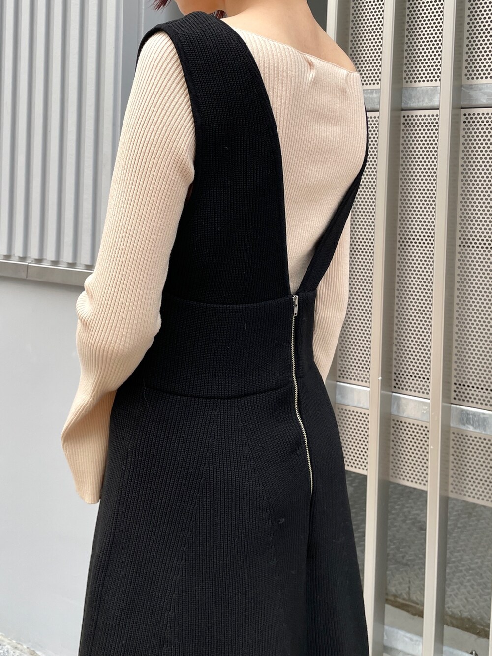 ホワイト系のニット/セーター、ブラック系のジャンパースカート、ブラック系のブーツを着用したレディースの冬コーディネートの6枚目の写真