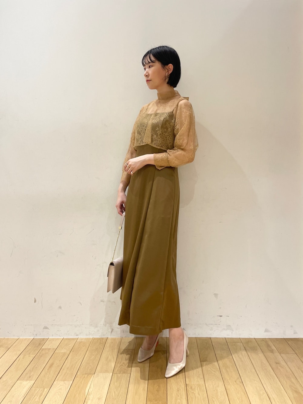 ブラウン系のドレス、ベージュ系のクラッチバッグ、ベージュ系のパンプスを着用したレディースの夏コーディネートの3枚目の写真