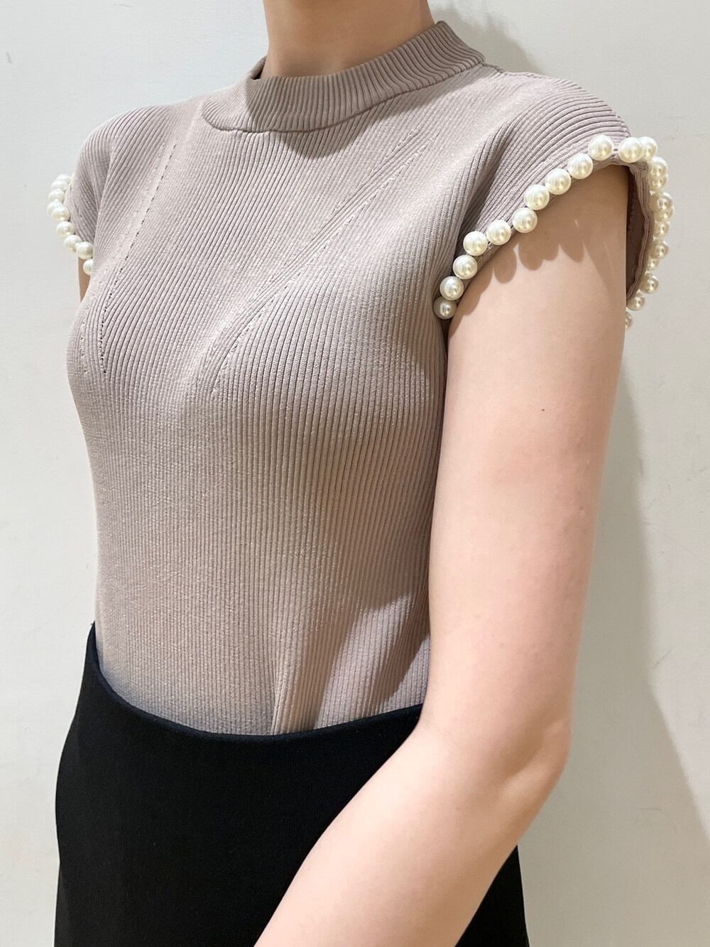 ブラック系のスカート、ベージュ系のニット/セーター、ホワイト系のショルダーバッグを着用したレディースの夏コーディネートの7枚目の写真