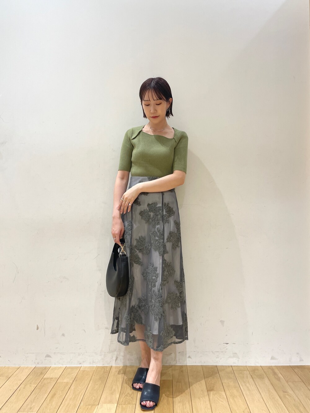 ベージュ系のブーツ、グリーン系のニット/セーター、グレー系のスカートを着用したレディースの夏コーディネートの6枚目の写真