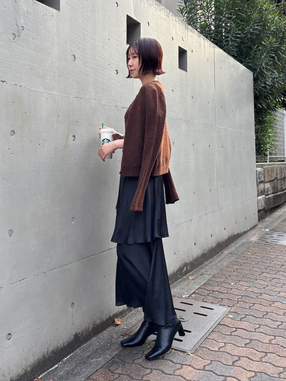 ブラック系のスカート、ブラウン系のアンサンブル、ブラック系のブーツを着用したレディースの秋コーディネートの3枚目の写真