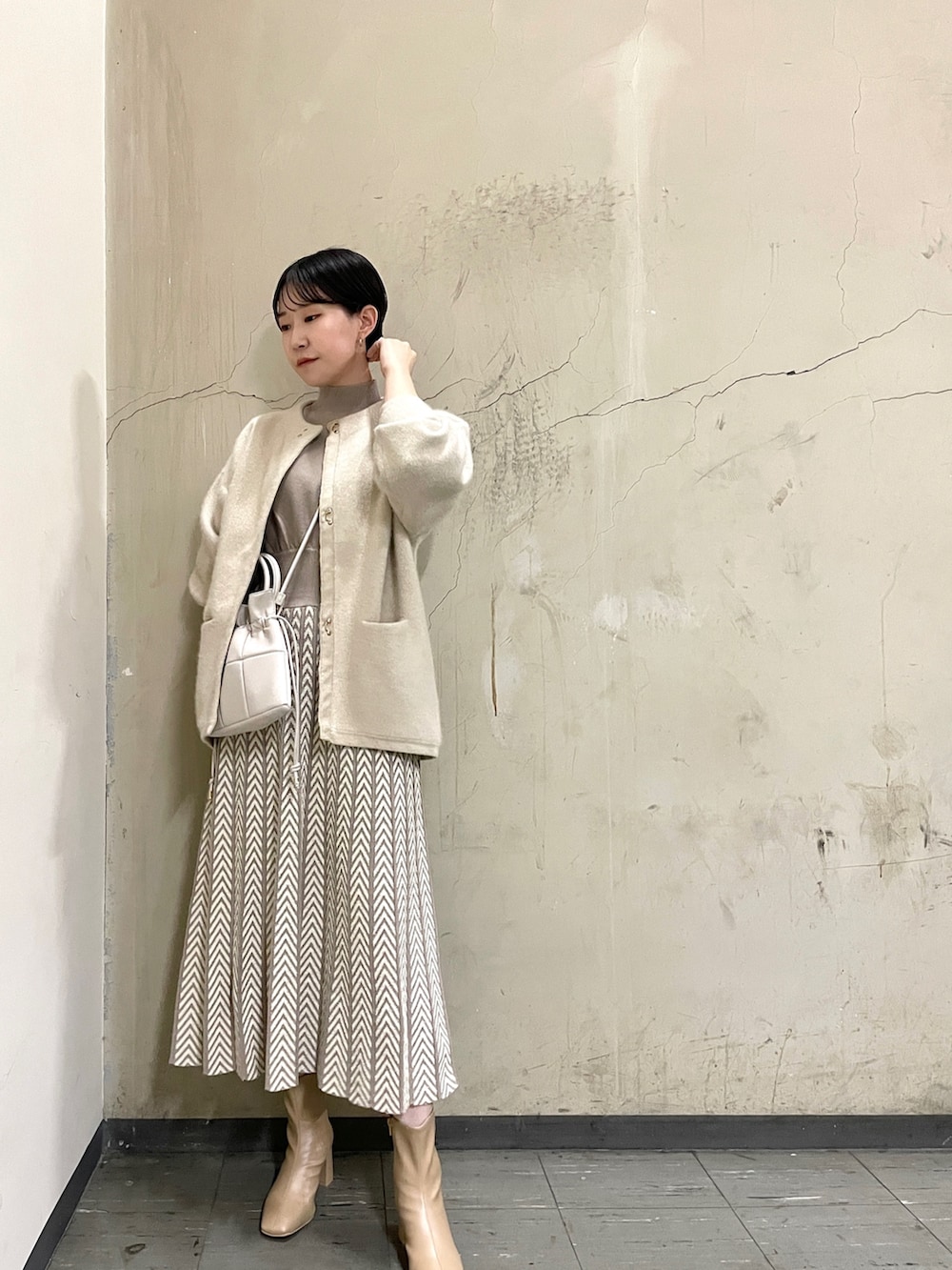 ホワイト系のカーディガン/ボレロ、ベージュ系のブーツ、ホワイト系のハンドバッグを着用したレディースの冬コーディネートの2枚目の写真