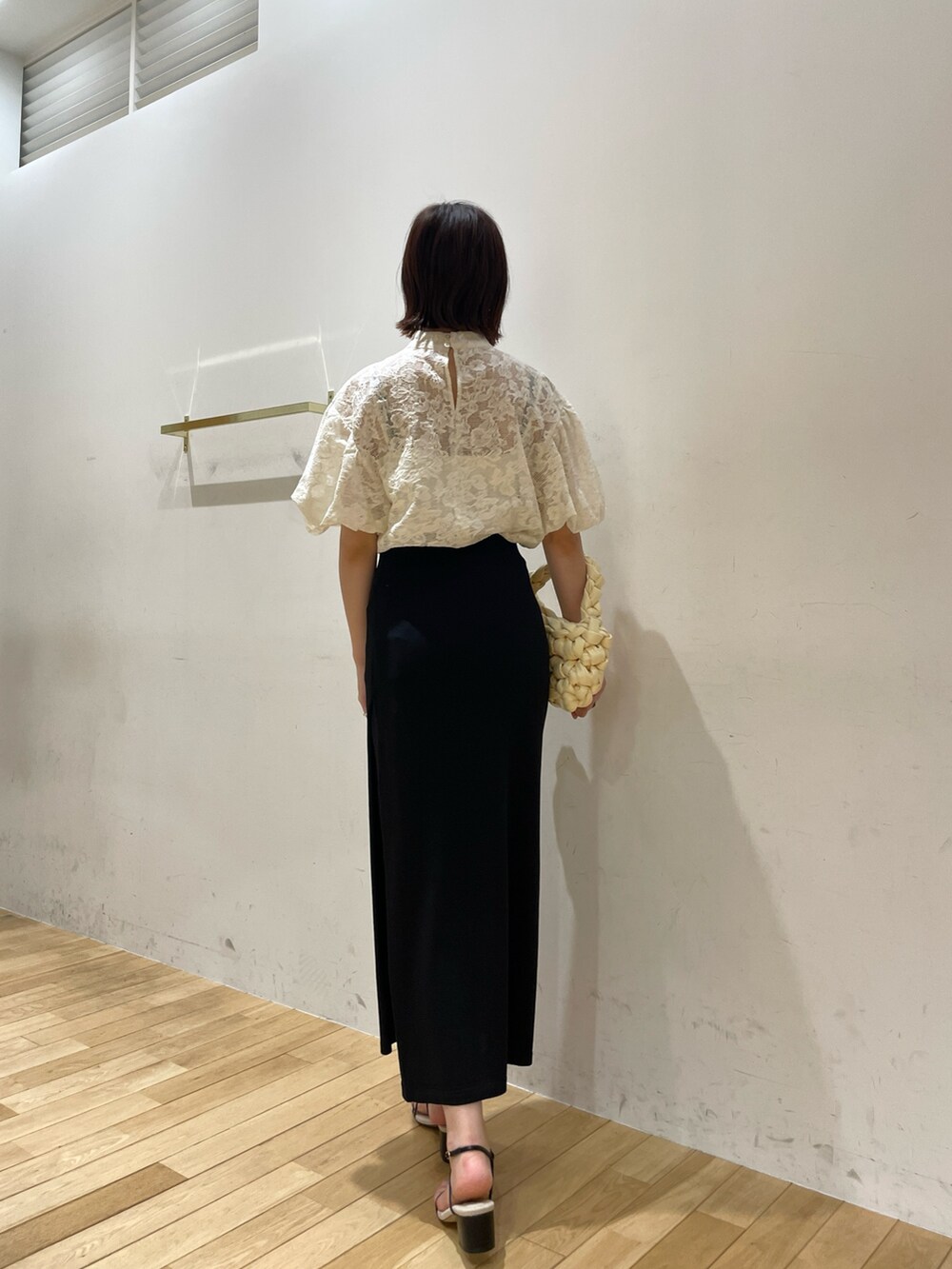 ベージュ系のハンドバッグ、ブラック系のサンダル、ホワイト系のシャツ/ブラウスを着用したレディースの夏コーディネートの5枚目の写真