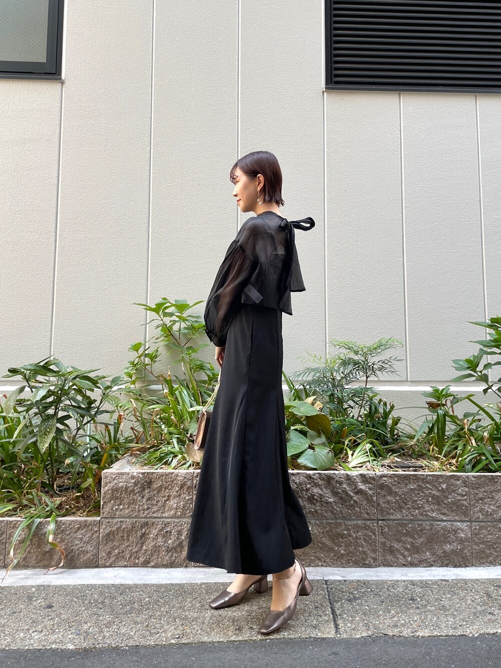 ブラック系のドレス、その他のパンプス、ゴールド系のハンドバッグを着用したレディースの秋コーディネートの4枚目の写真