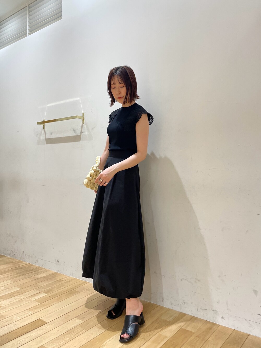 ベージュ系のハンドバッグ、ブラック系のサンダル、ブラック系のニット/セーターを着用したレディースの夏コーディネートの3枚目の写真