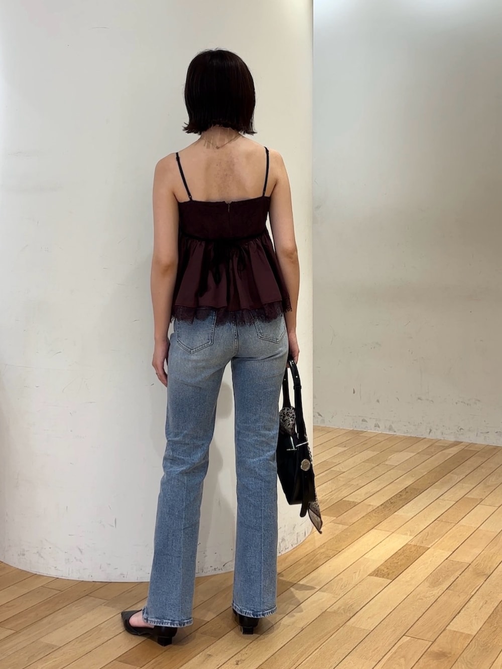 ブルー系のデニムパンツ、ブラック系のハンドバッグ、ブラック系のパンプスを着用したレディースの夏コーディネートの3枚目の写真