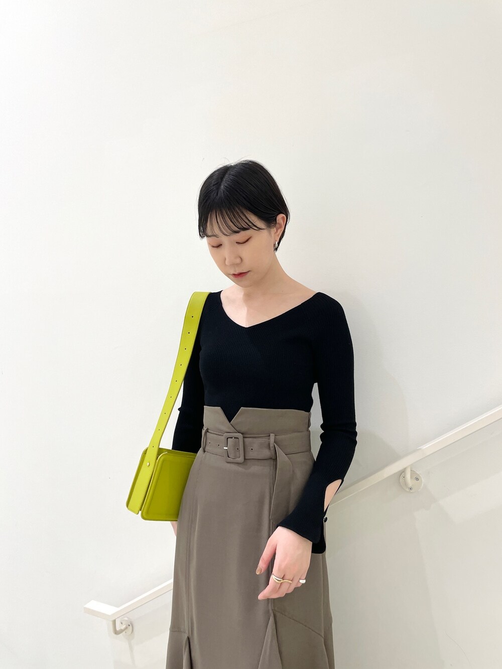 ブラウン系のスカート、ブラック系のニット/セーター、ベージュ系のサンダルを着用したレディースの春コーディネートの6枚目の写真