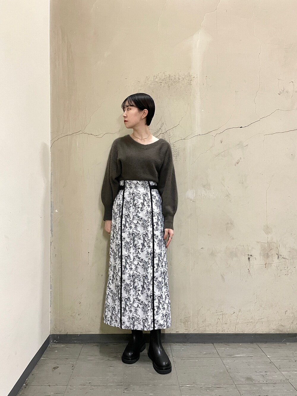 ブラック系のブーツ、ブラウン系のニット/セーター、ブラック系のスカートを着用したレディースの秋コーディネートの2枚目の写真