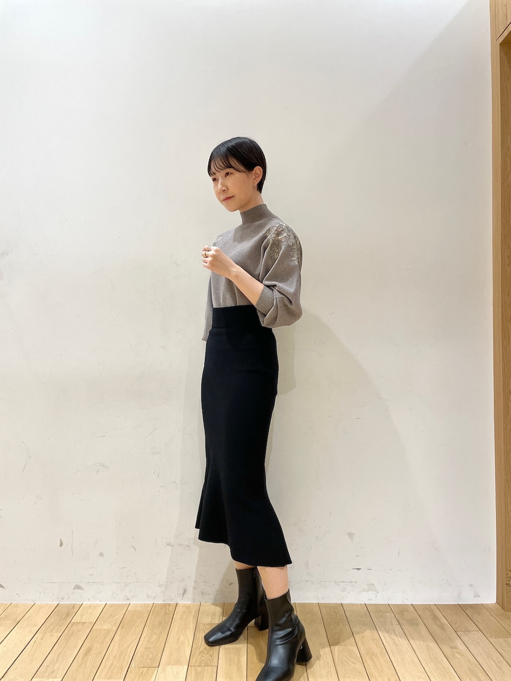 ブラック系のスカート、グレー系のニット/セーター、ブラック系のブーツを着用したレディースの冬コーディネートの2枚目の写真