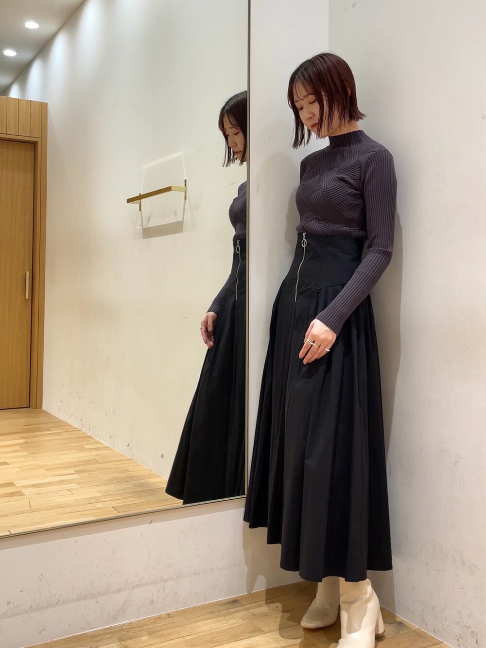 ホワイト系のブーツ、ブラック系のスカート、グレー系のニット/セーターを着用したレディースの冬コーディネートの3枚目の写真