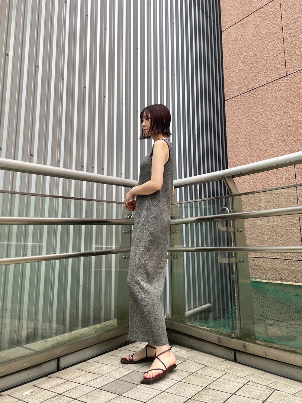 ブラウン系のサンダル、ブラック系のワンピースを着用したレディースの夏コーディネートの2枚目の写真