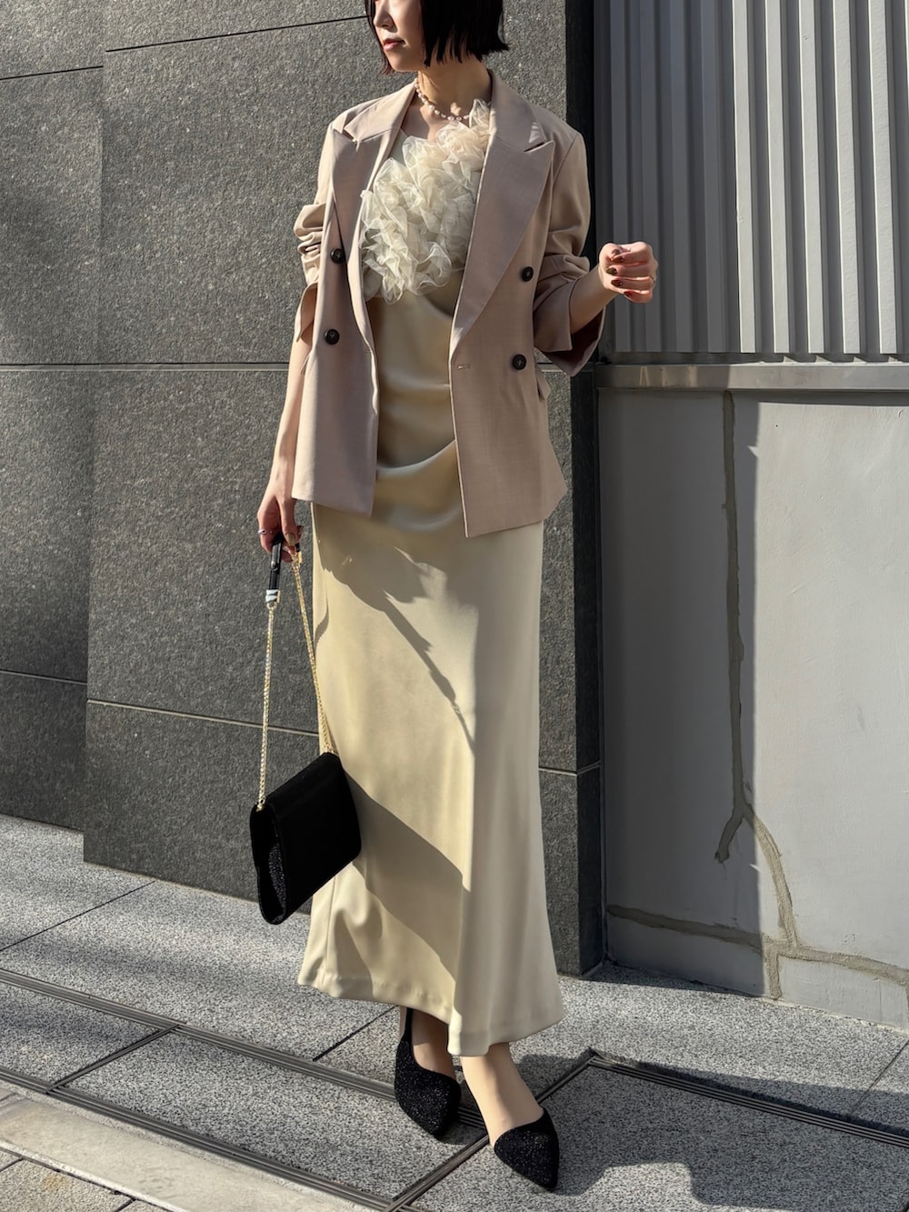 イエロー系のドレス、ブラック系のハンドバッグ、ブラック系のパンプスを着用したレディースの冬コーディネートの6枚目の写真