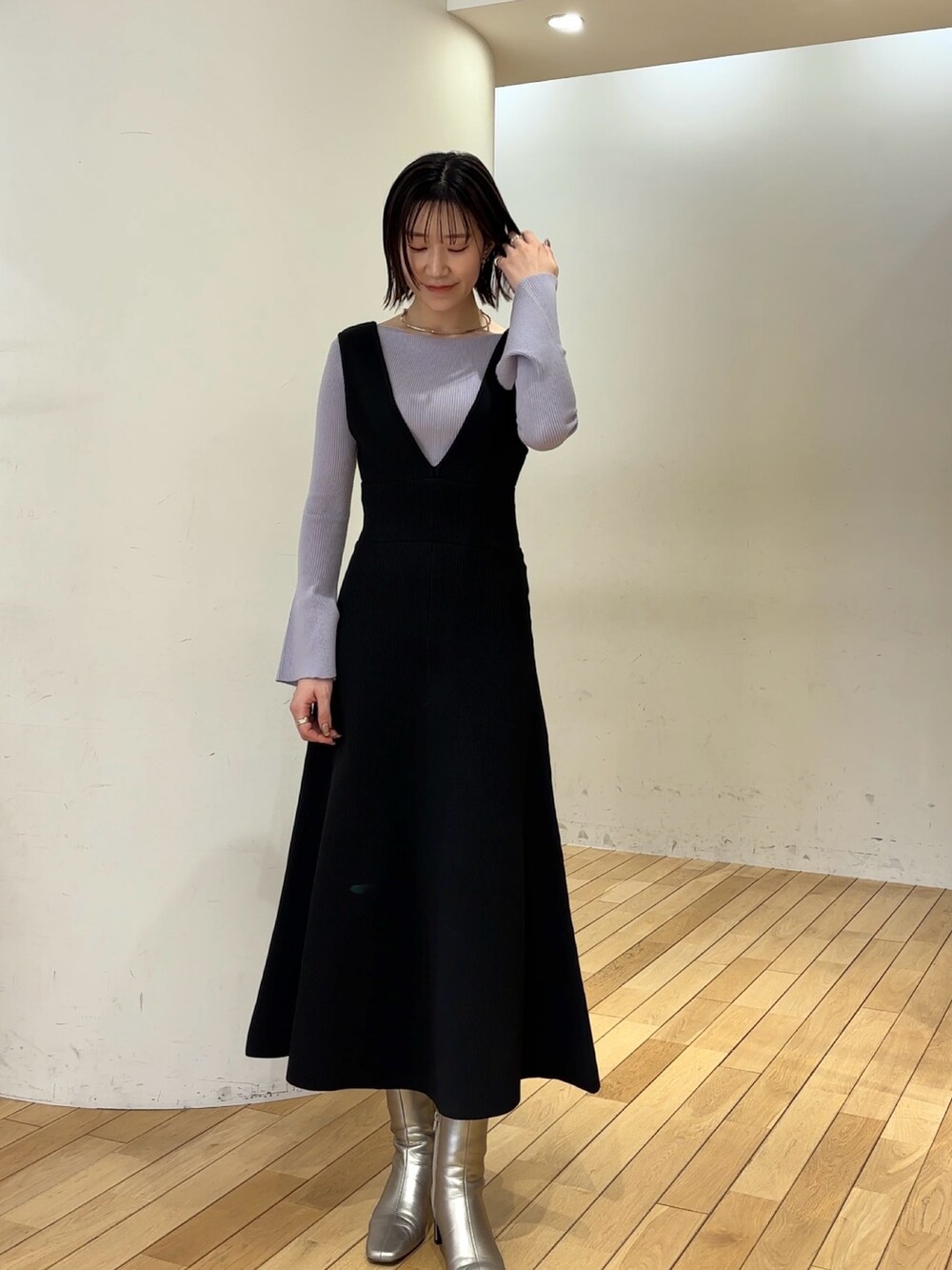 ブラック系のジャンパースカート、パープル系のニット/セーター、シルバー系のブーツを着用したレディースの冬コーディネートの2枚目の写真