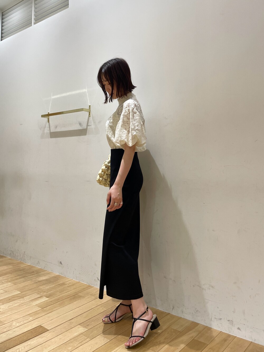 ベージュ系のハンドバッグ、ブラック系のサンダル、ホワイト系のシャツ/ブラウスを着用したレディースの夏コーディネートの4枚目の写真