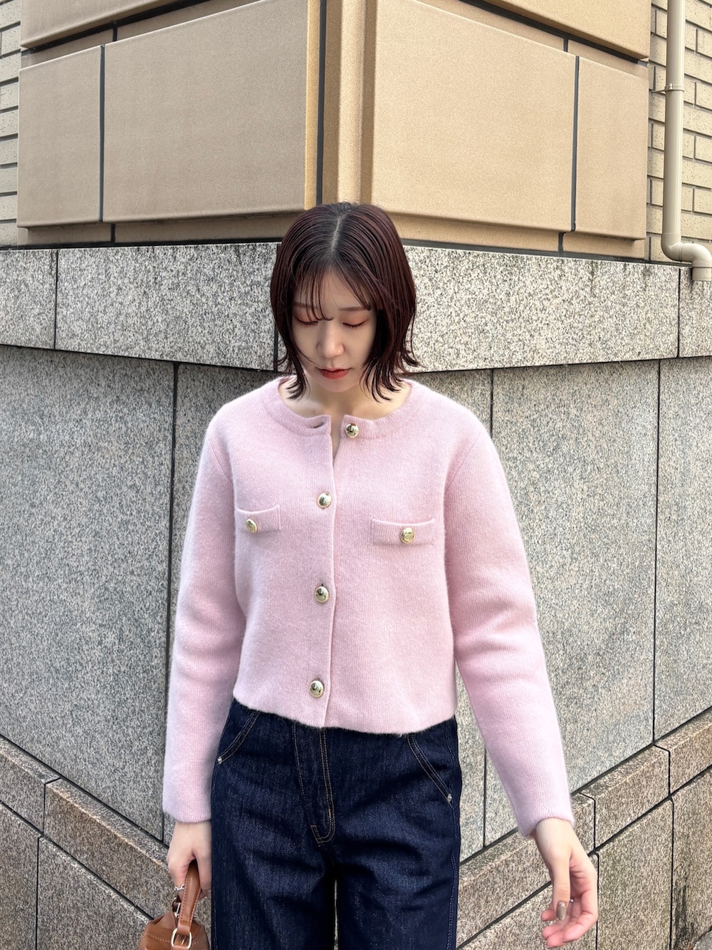 ブルー系のデニムパンツ、ピンク系のテーラードジャケット、イエロー系のハンドバッグを着用したレディースの冬コーディネートの4枚目の写真