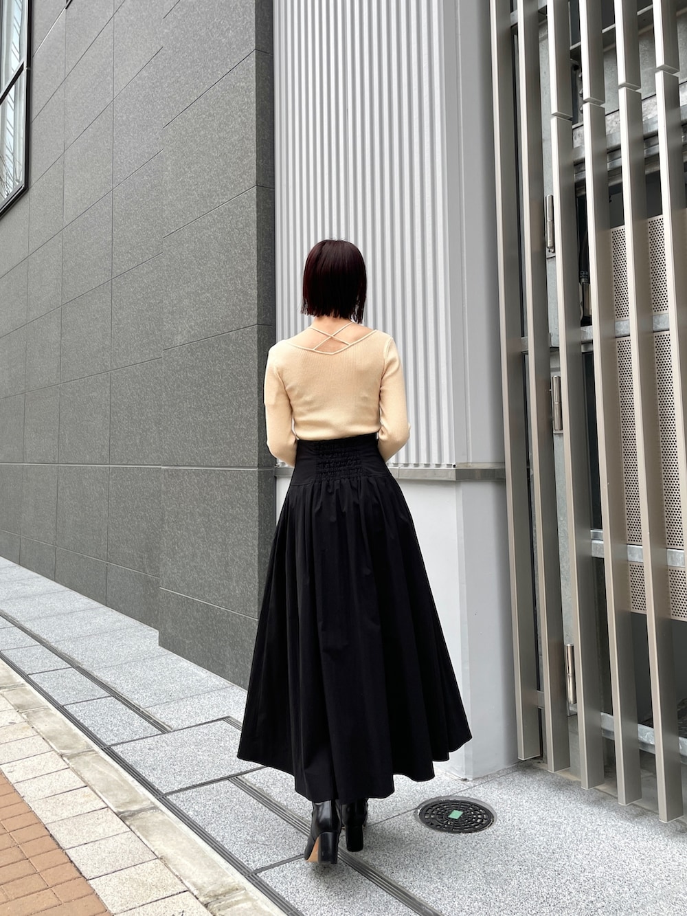 ブラック系のブーツ、ホワイト系のニット/セーター、ブラック系のスカートを着用したレディースの冬コーディネートの4枚目の写真