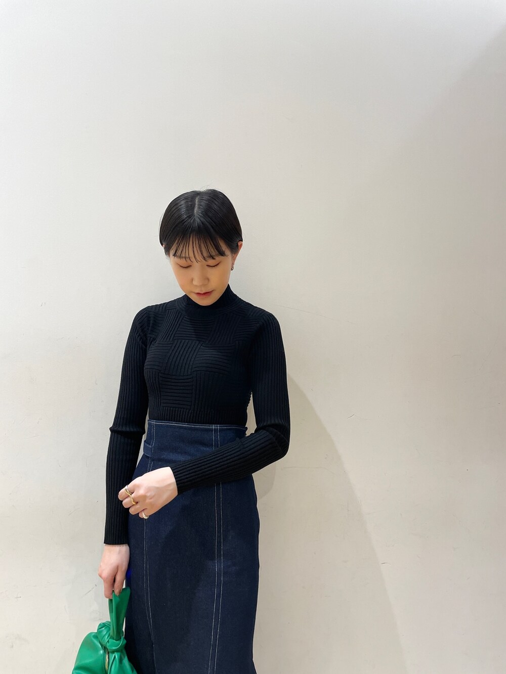 ブルー系のスカート、ブラック系のニット/セーター、グリーン系のハンドバッグを着用したレディースの冬コーディネートの6枚目の写真