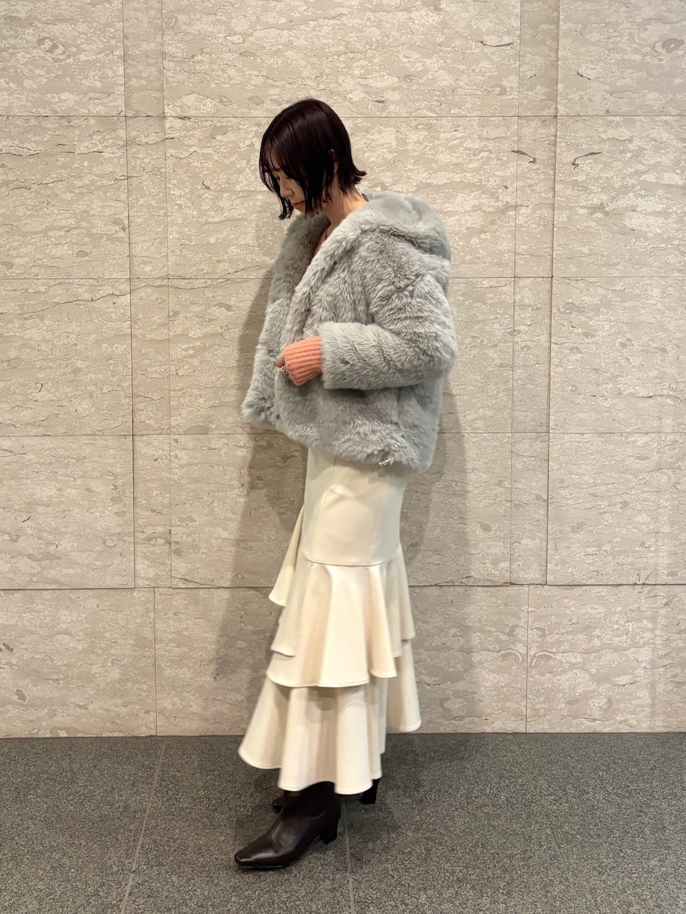 ピンク系のニット/セーター、ブラウン系のブーツ、ホワイト系のスカートを着用したレディースの冬コーディネートの3枚目の写真