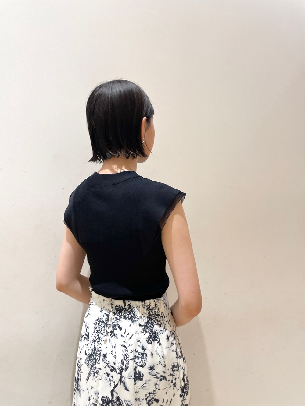 ブラック系のニット/セーター、ブルー系のスカート、ブラック系のハンドバッグを着用したレディースの夏コーディネートの6枚目の写真