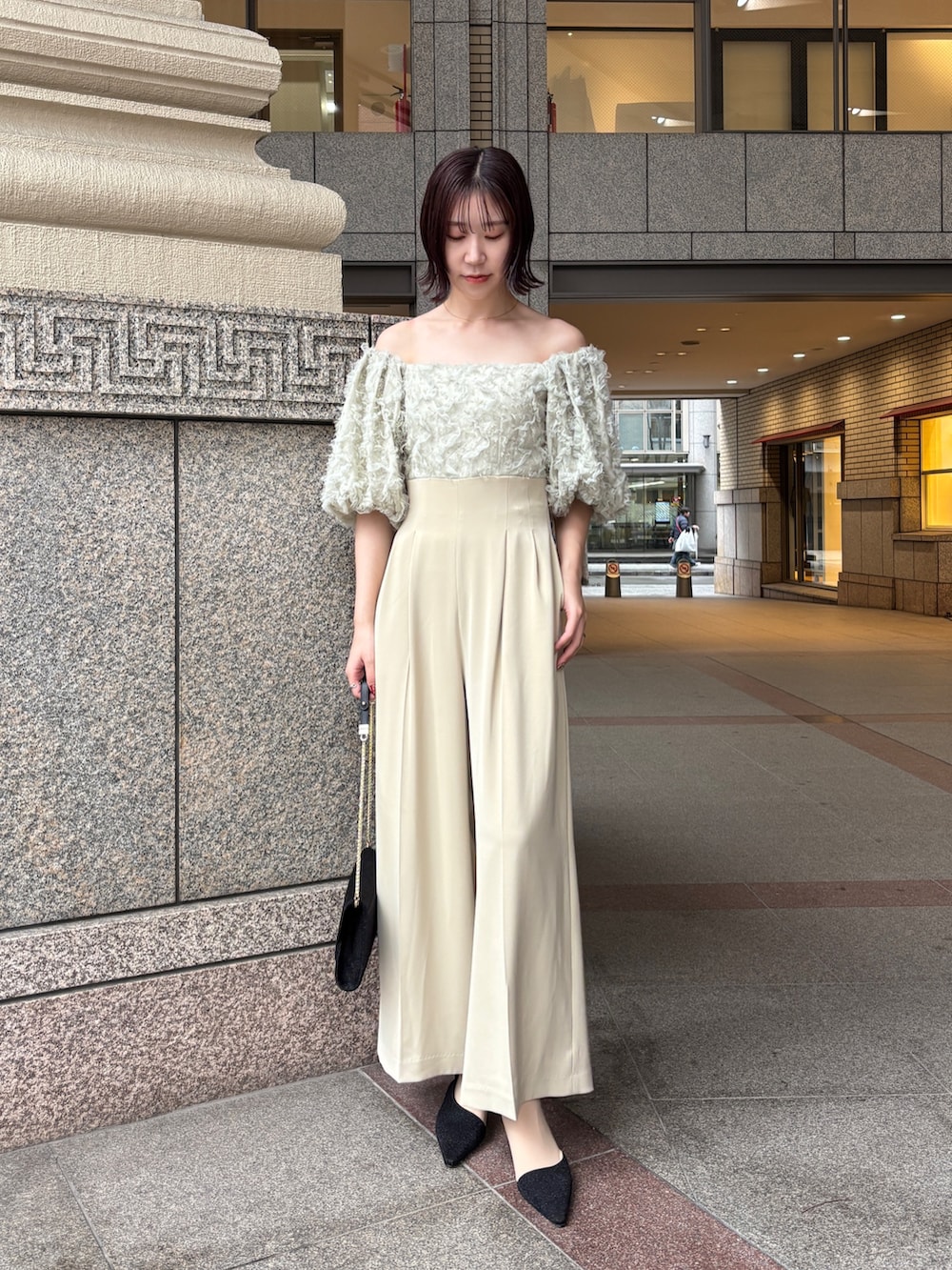 グリーン系のパンツドレス、ブラック系のパンプス、ブラック系のハンドバッグを着用したレディースの冬コーディネートの4枚目の写真