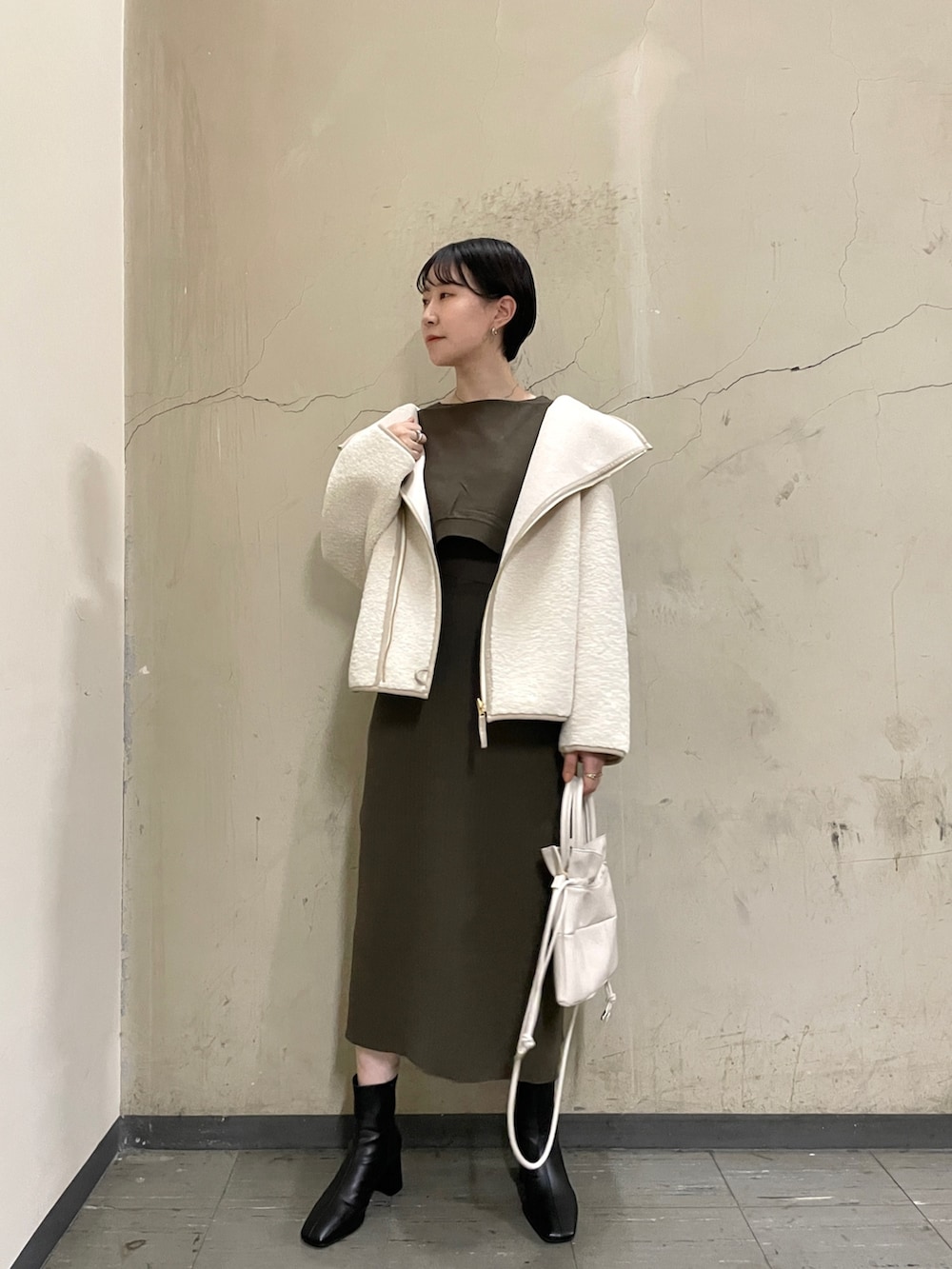 ホワイト系のブルゾン、ブラック系のブーツ、ブラウン系のワンピースを着用したレディースの秋コーディネートの2枚目の写真