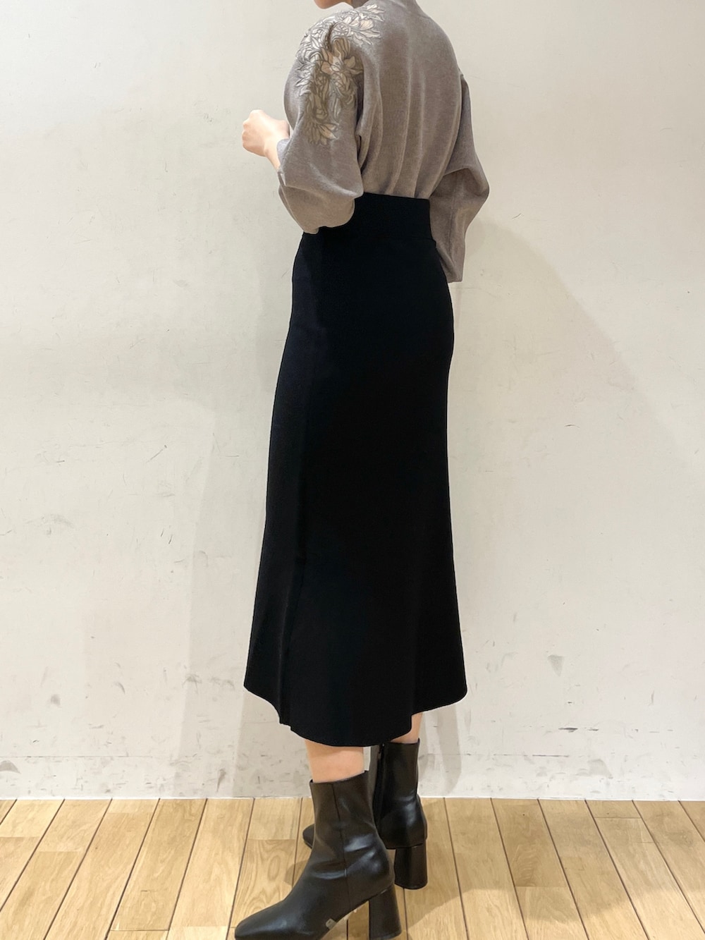 ブラック系のスカート、グレー系のニット/セーター、ブラック系のブーツを着用したレディースの冬コーディネートの4枚目の写真