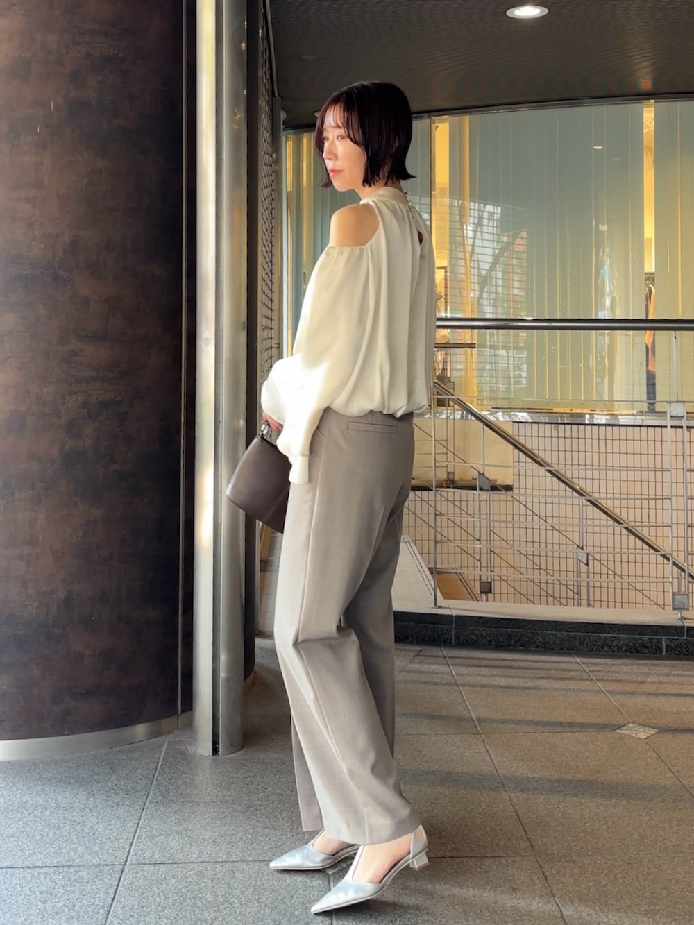 シルバー系のパンプス、ブラウン系のハンドバッグ、グレー系のその他パンツを着用したレディースの冬コーディネートの3枚目の写真