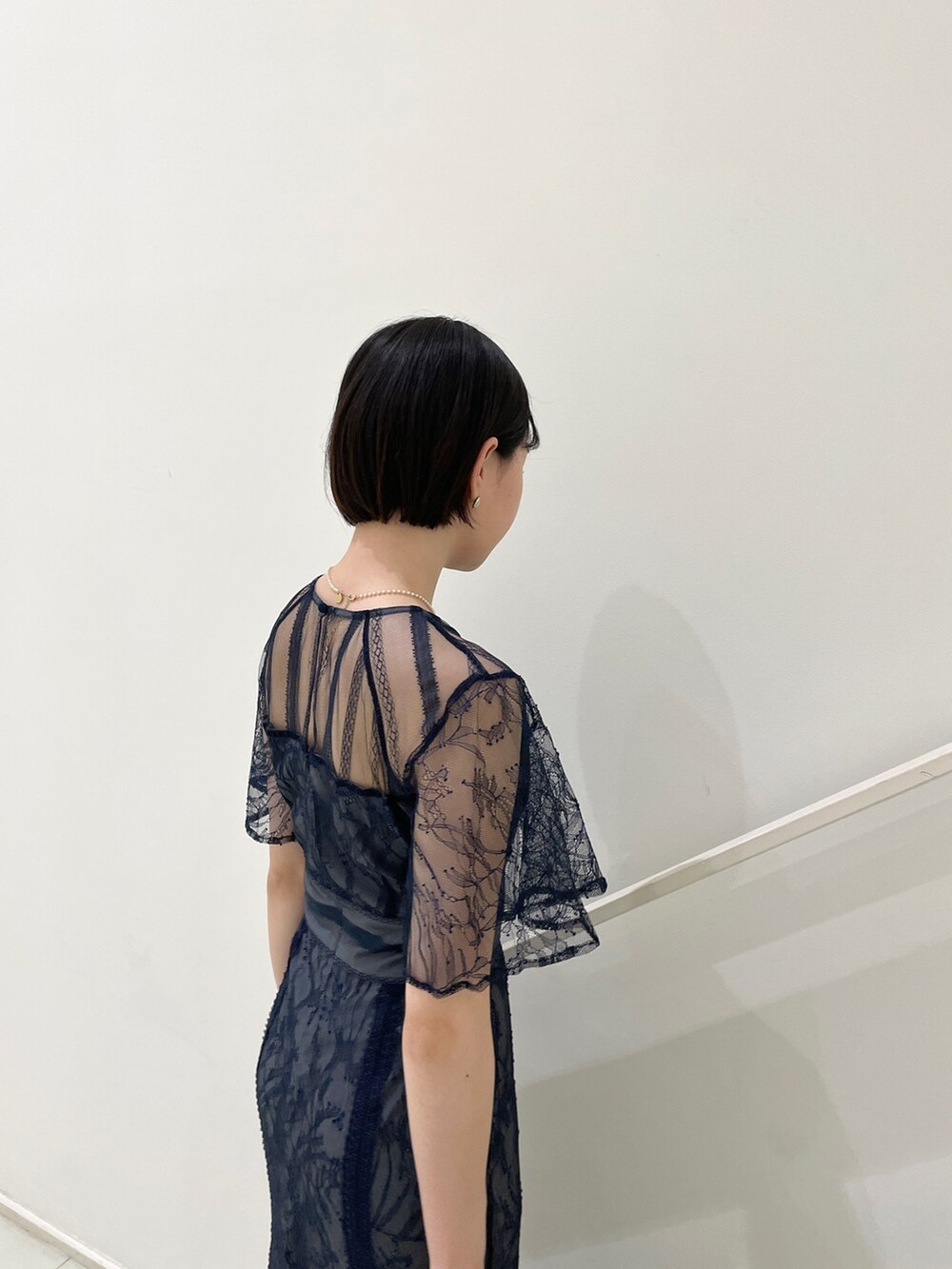 ブルー系のドレス、ゴールド系のパンプス、ホワイト系のネックレスを着用したレディースの春コーディネートの7枚目の写真