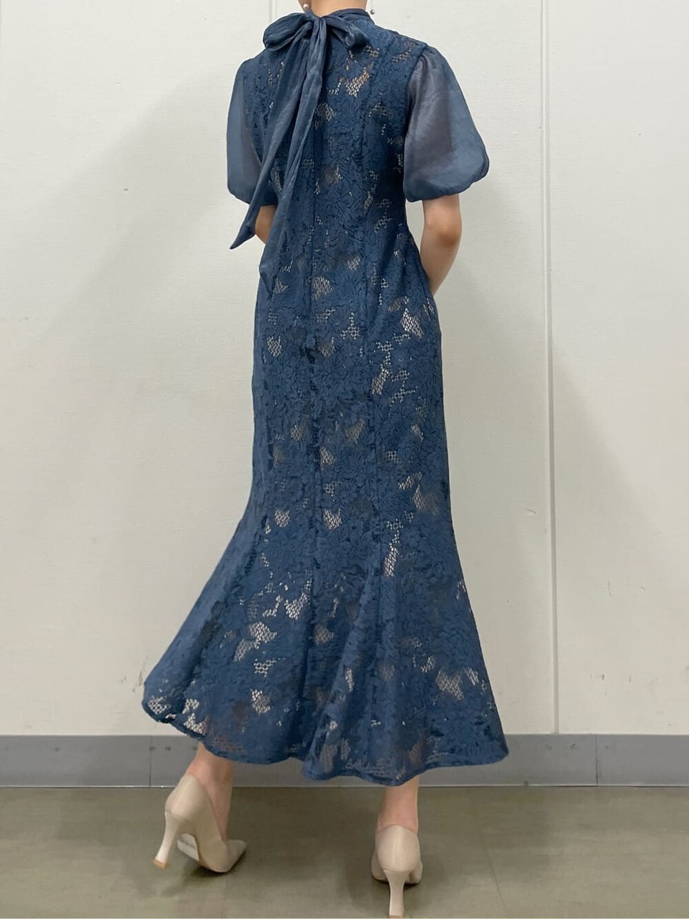 シルバー系のクラッチバッグ、ベージュ系のパンプス、ブルー系のドレスを着用したレディースの夏コーディネートの4枚目の写真