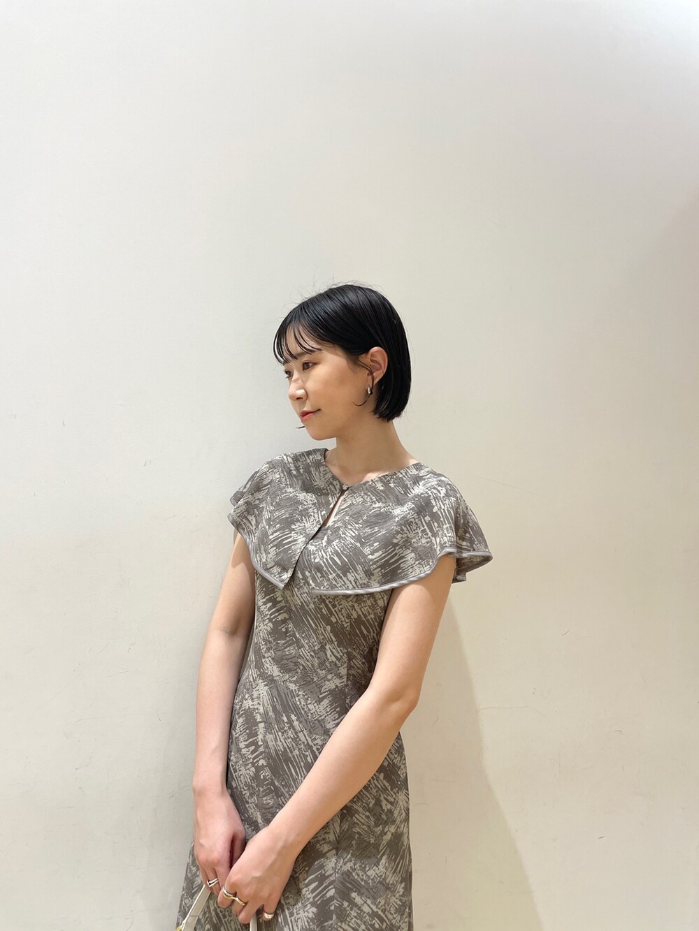 グレー系のワンピース、ホワイト系のハンドバッグ、ベージュ系のサンダルを着用したレディースの夏コーディネートの7枚目の写真