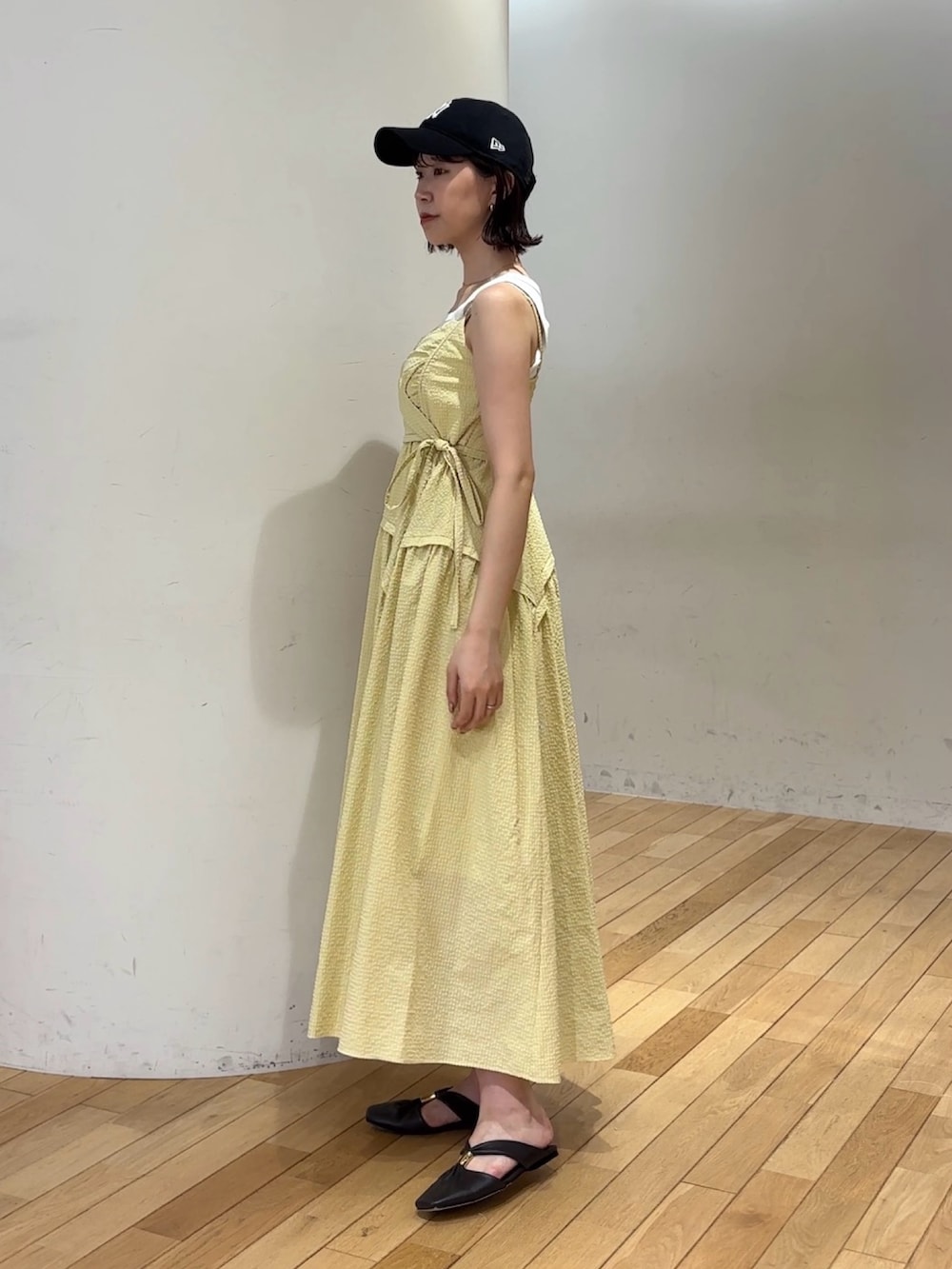 イエロー系のワンピース、ホワイト系のタンクトップ、ブラウン系のハンドバッグを着用したレディースの夏コーディネートの3枚目の写真
