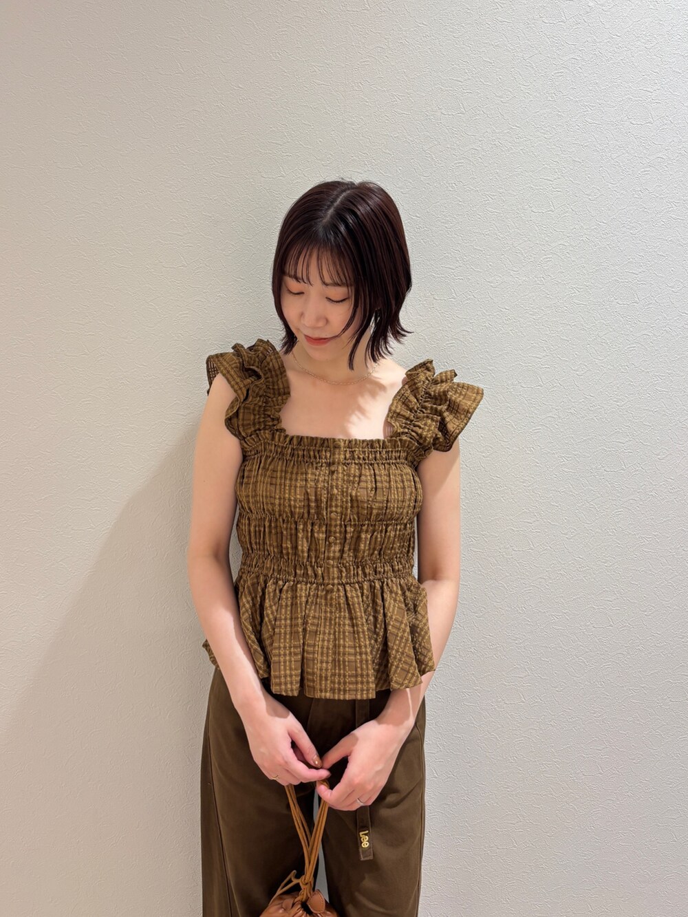 イエロー系のハンドバッグ、ブラウン系のデニムパンツ、ブラウン系のシャツ/ブラウスを着用したレディースの夏コーディネートの4枚目の写真