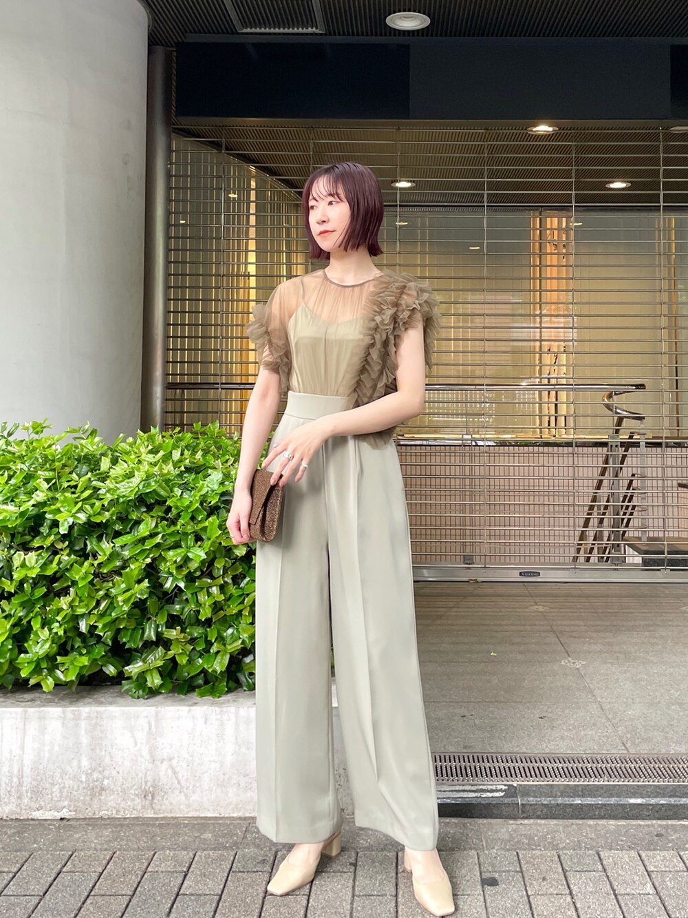 グリーン系のパンツドレス、ベージュ系のパンプスを着用したレディースの春コーディネートの2枚目の写真