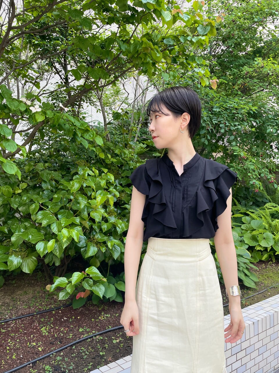 ホワイト系のスカート、ホワイト系のサンダル、ブラック系のシャツ/ブラウスを着用したレディースの夏コーディネートの5枚目の写真