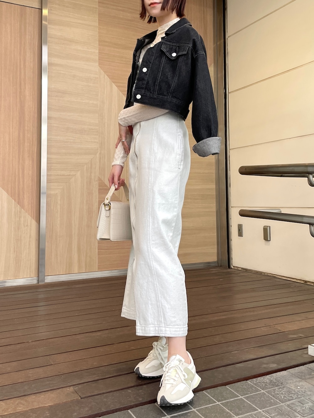 ホワイト系のショルダーバッグ、ホワイト系のワンピース、ブラック系のデニムジャケットを着用したレディースの春コーディネートの7枚目の写真