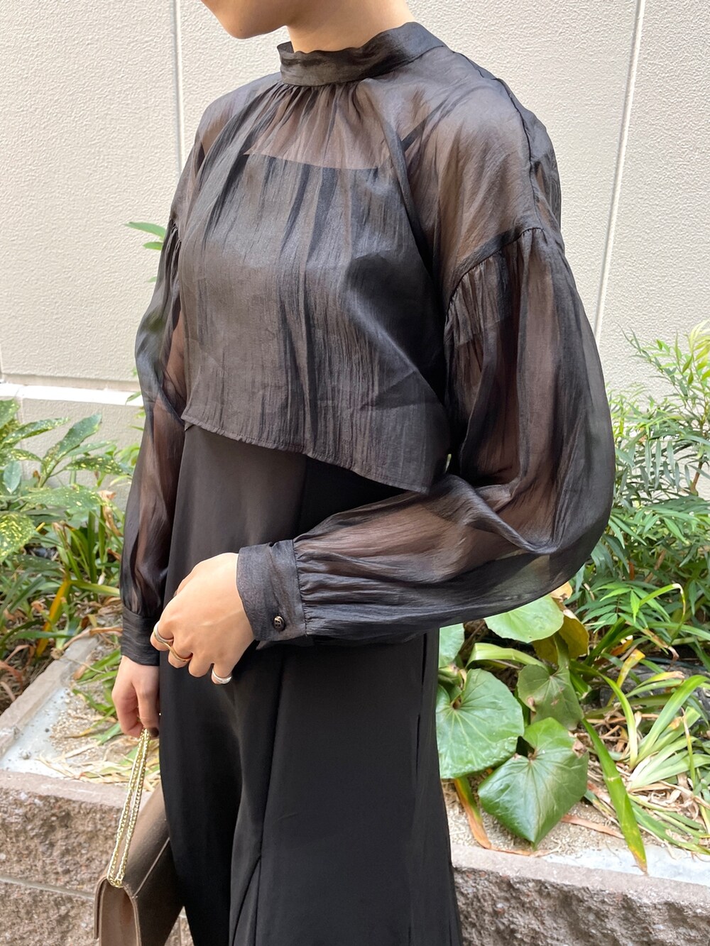 ブラック系のドレス、その他のパンプス、ゴールド系のハンドバッグを着用したレディースの秋コーディネートの7枚目の写真