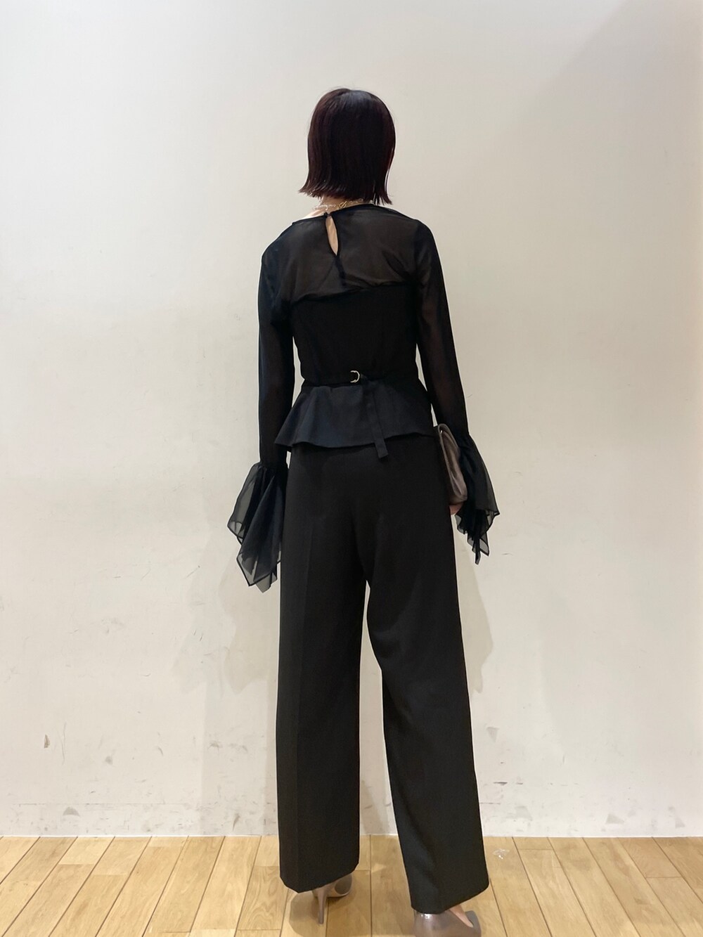 シルバー系のハンドバッグ、シルバー系のパンプス、ブラック系のパンツドレスを着用したレディースの秋コーディネートの5枚目の写真