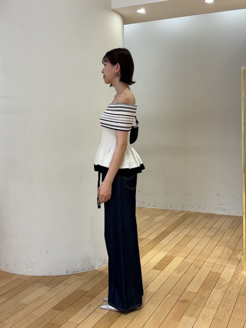 ホワイト系のニット/セーター、ブルー系のデニムパンツ、ブラック系のハンドバッグを着用したレディースの夏コーディネートの3枚目の写真