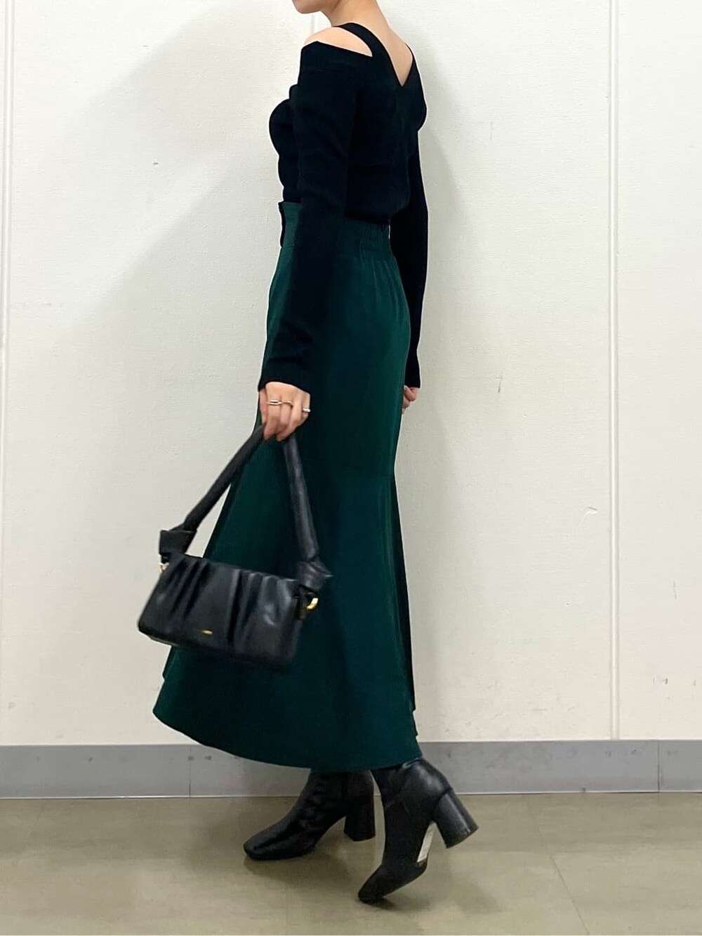 グリーン系のスカート、ブラック系のブーツ、ブラック系のニット/セーターを着用したレディースの秋コーディネートの4枚目の写真