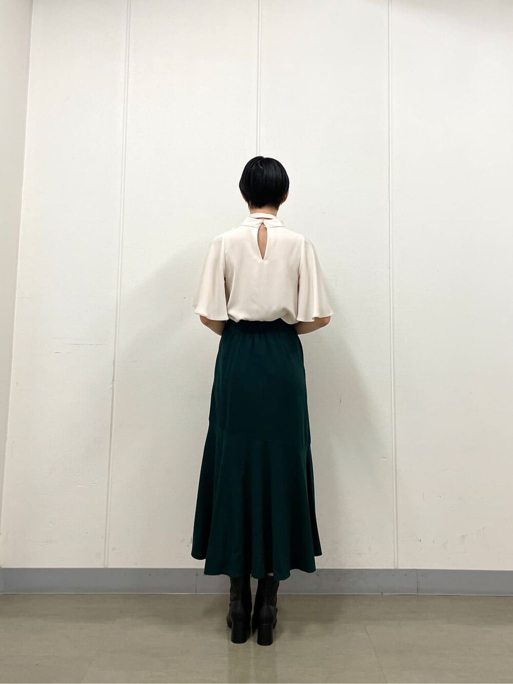 ホワイト系のシャツ/ブラウス、グリーン系のスカート、ブラック系のブーツを着用したレディースの秋コーディネートの4枚目の写真
